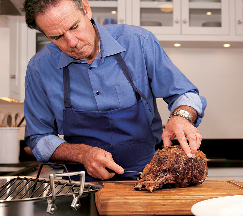 Chef de-boning and carving a portion of barbecued prime rib steak