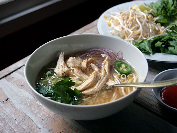 pho with bone broth in white bowl on wooden table