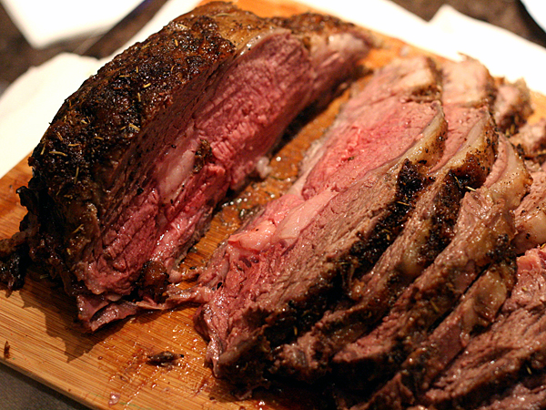 prime rib, roasted and sliced on wooden cutting board