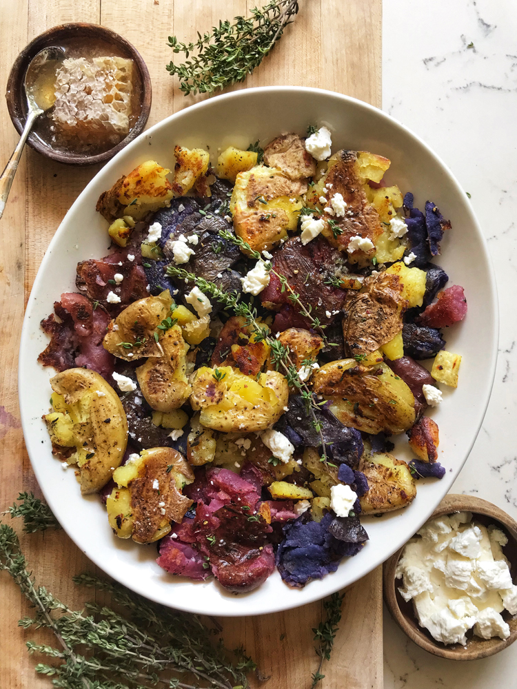 crispy smashed red white and blue potatoes in white oval dish