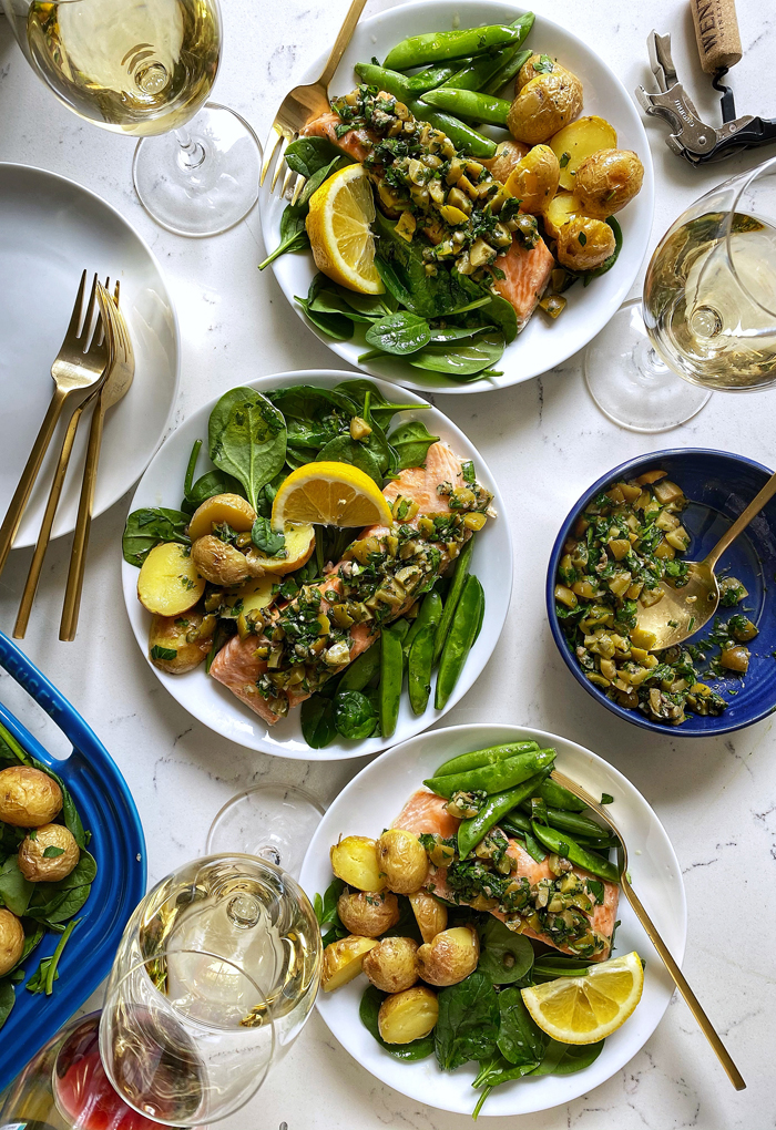 salmon with green olive salsa verde, roasted snap peas, and baby spinach salad on plates