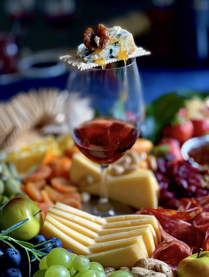 blue cheese walnut and honey on cracker on balanced wine glass