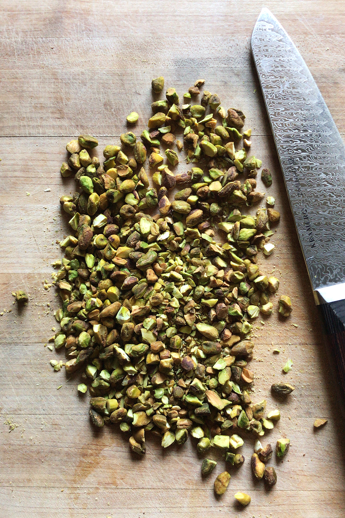 chopped pistachios on cutting board with chef's knife