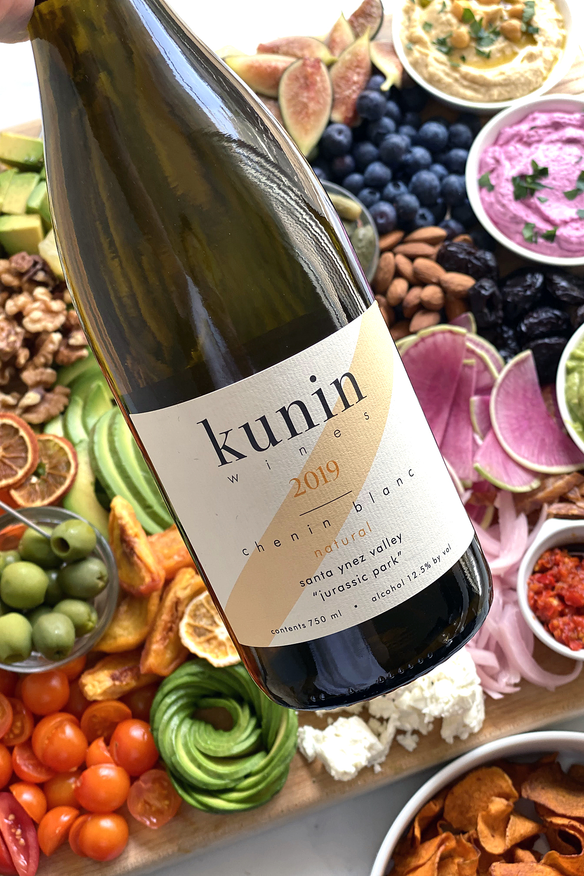 kunin wines natural chenin blanc bottle in front of vegetable crudites with avocado