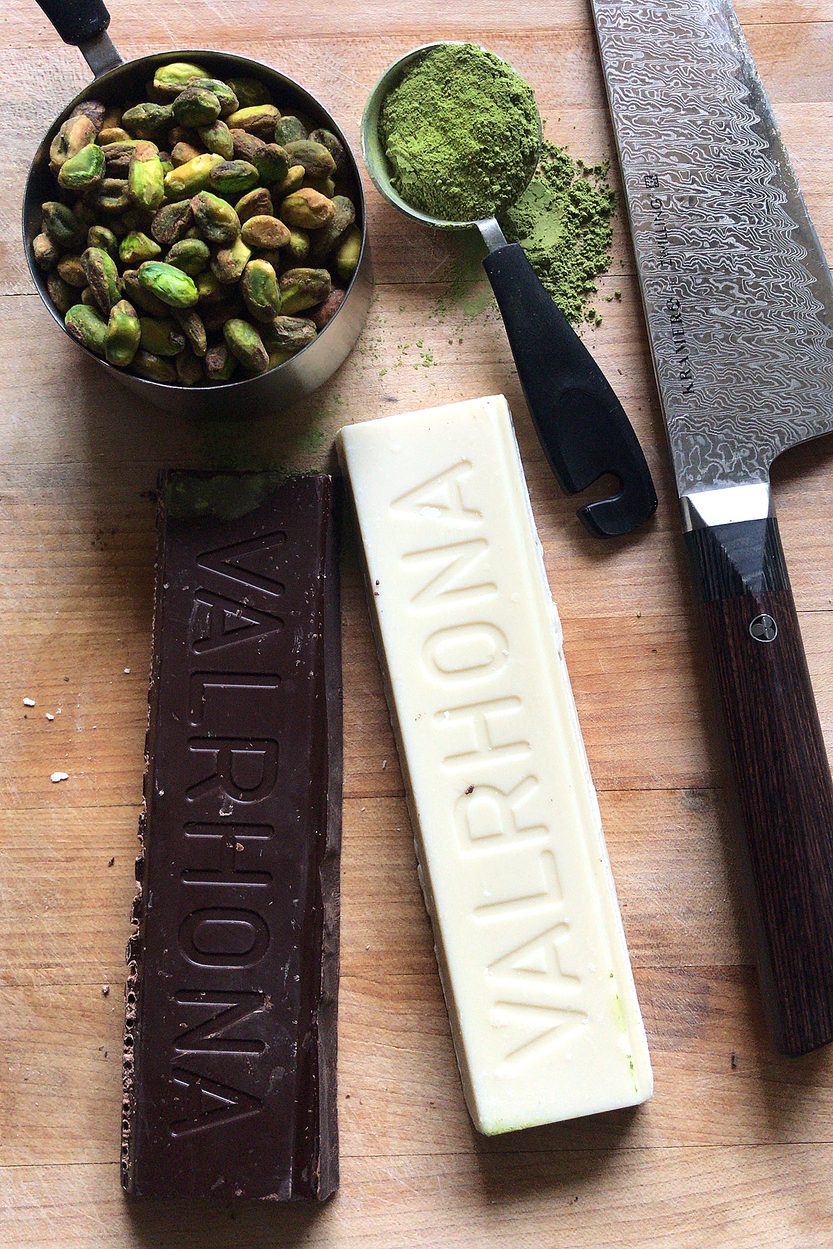 dark and white chocolate baking bars by valrhona on cutting board with pistachios and matcha