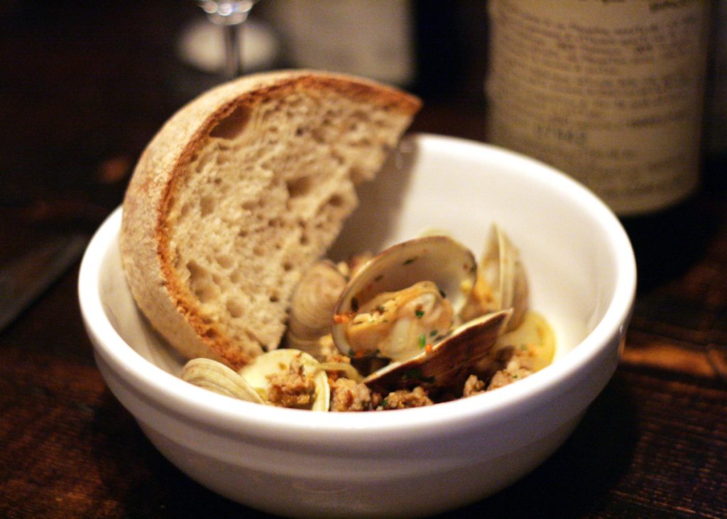 clasm, spicy italian sausage, white wine with pasta in white bowl with bread