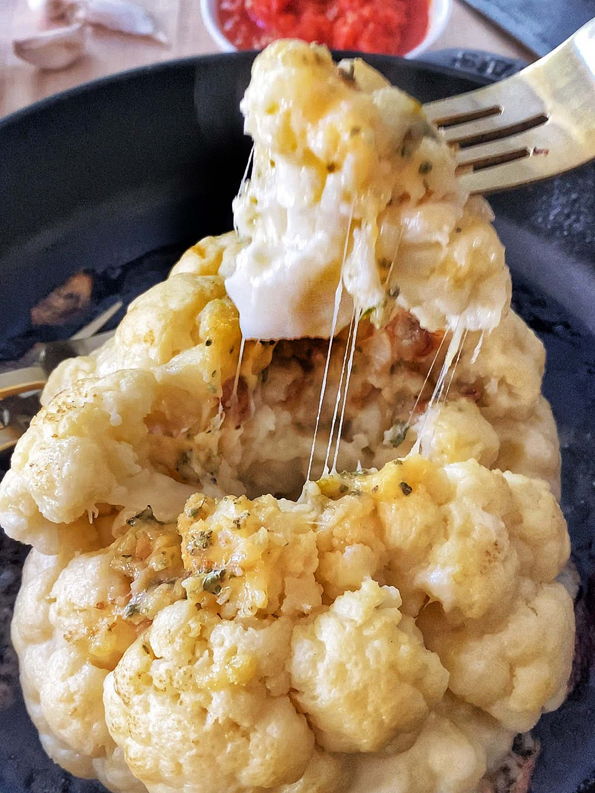 oven roasted whole cauliflower stuffed with cheese, one floret pulled out