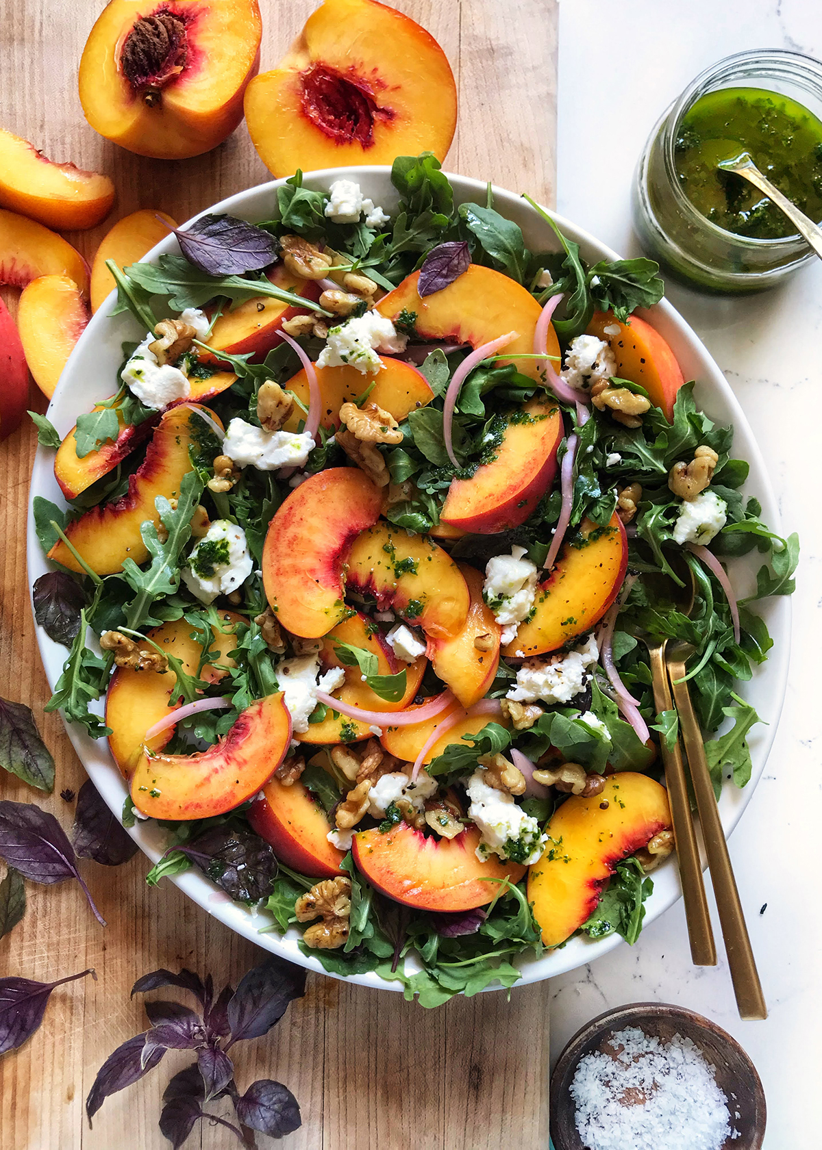 peach arugula salad in white oval bowl on wooden cutting board