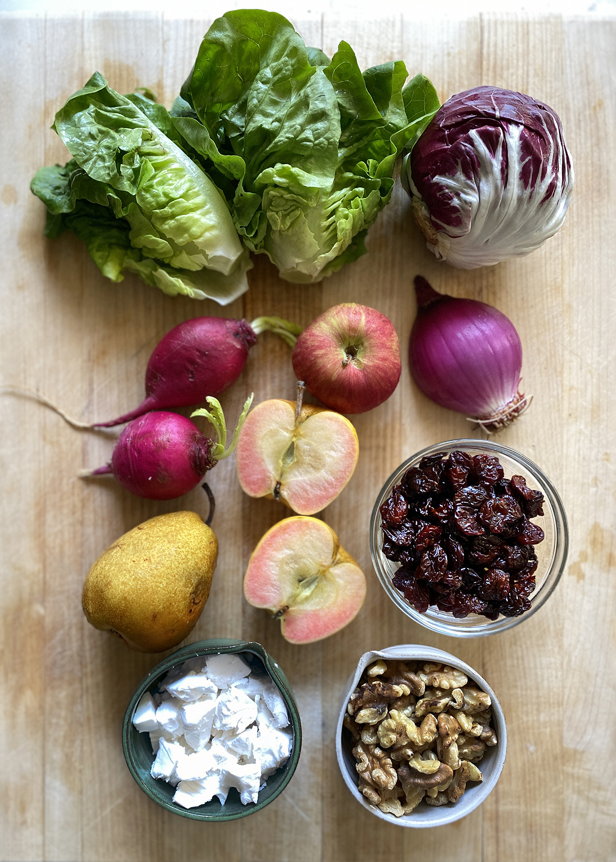 romaine lettuce radicchio apples walnuts and cherries on cutting board