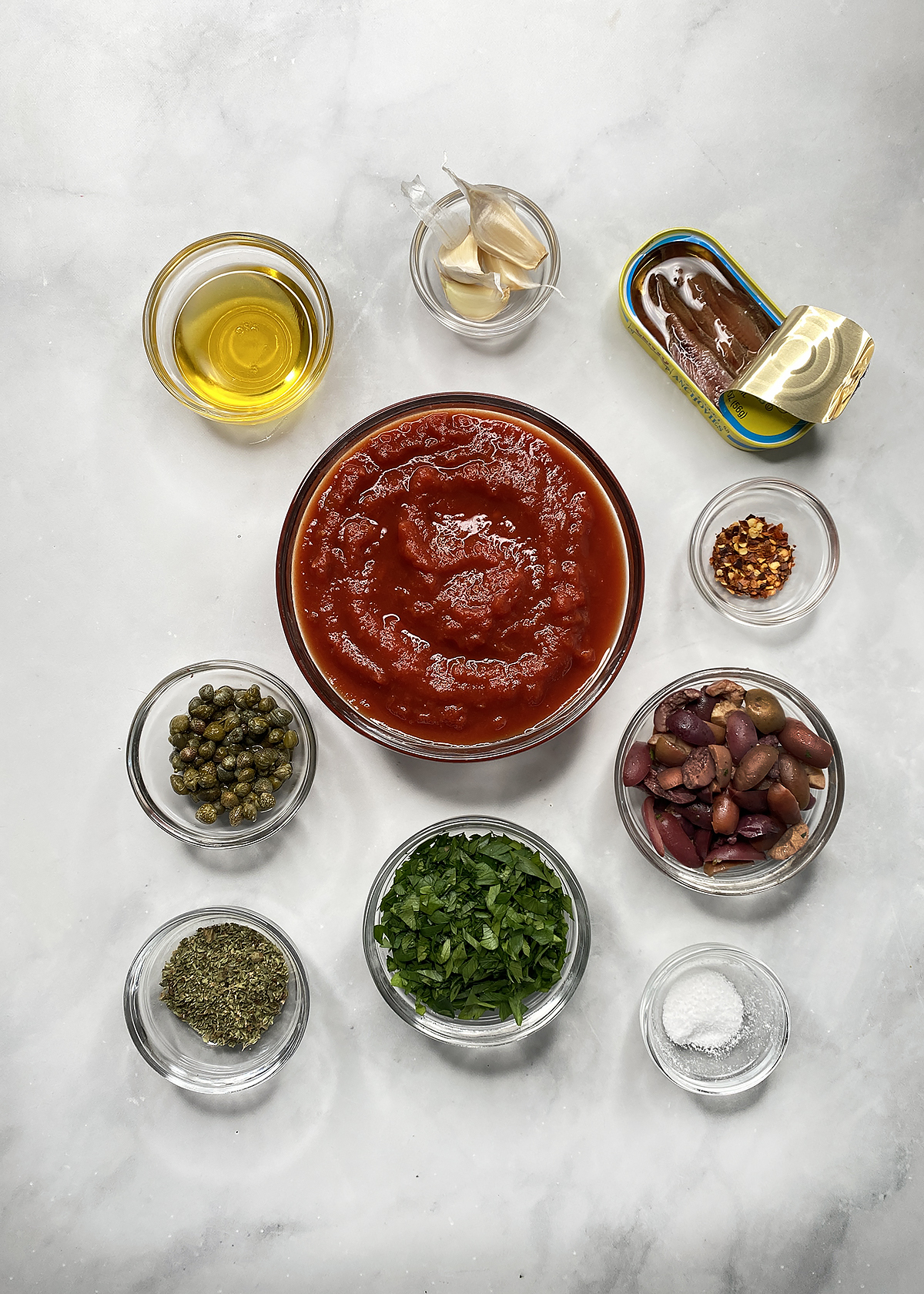 puttanesca ingredients in individual glass bowls