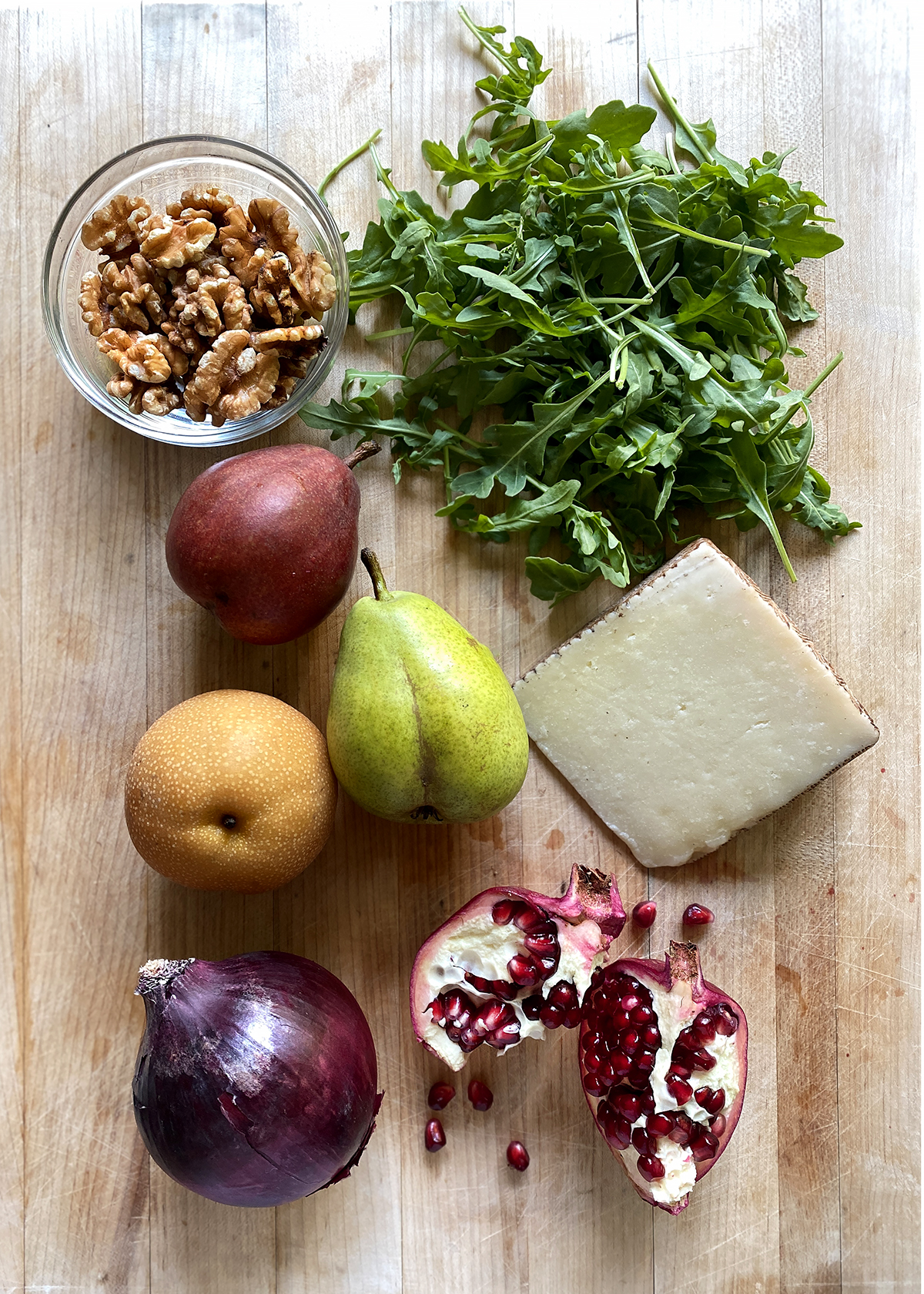 arugula pear salad ingredients on a wooden cutting board