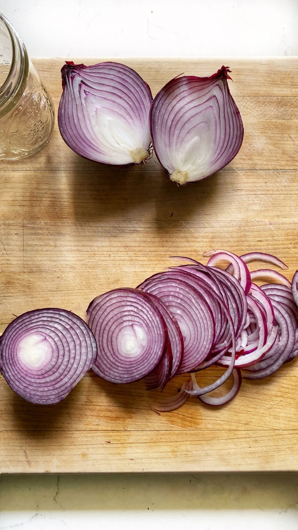 red onions cut two ways, vertically and horizontally, on a wooden cutting board