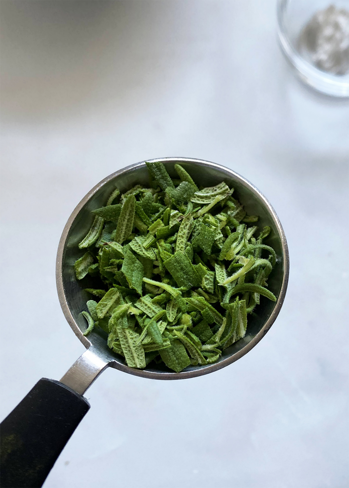 minced fresh rosemary in tablespoon measuring spoon