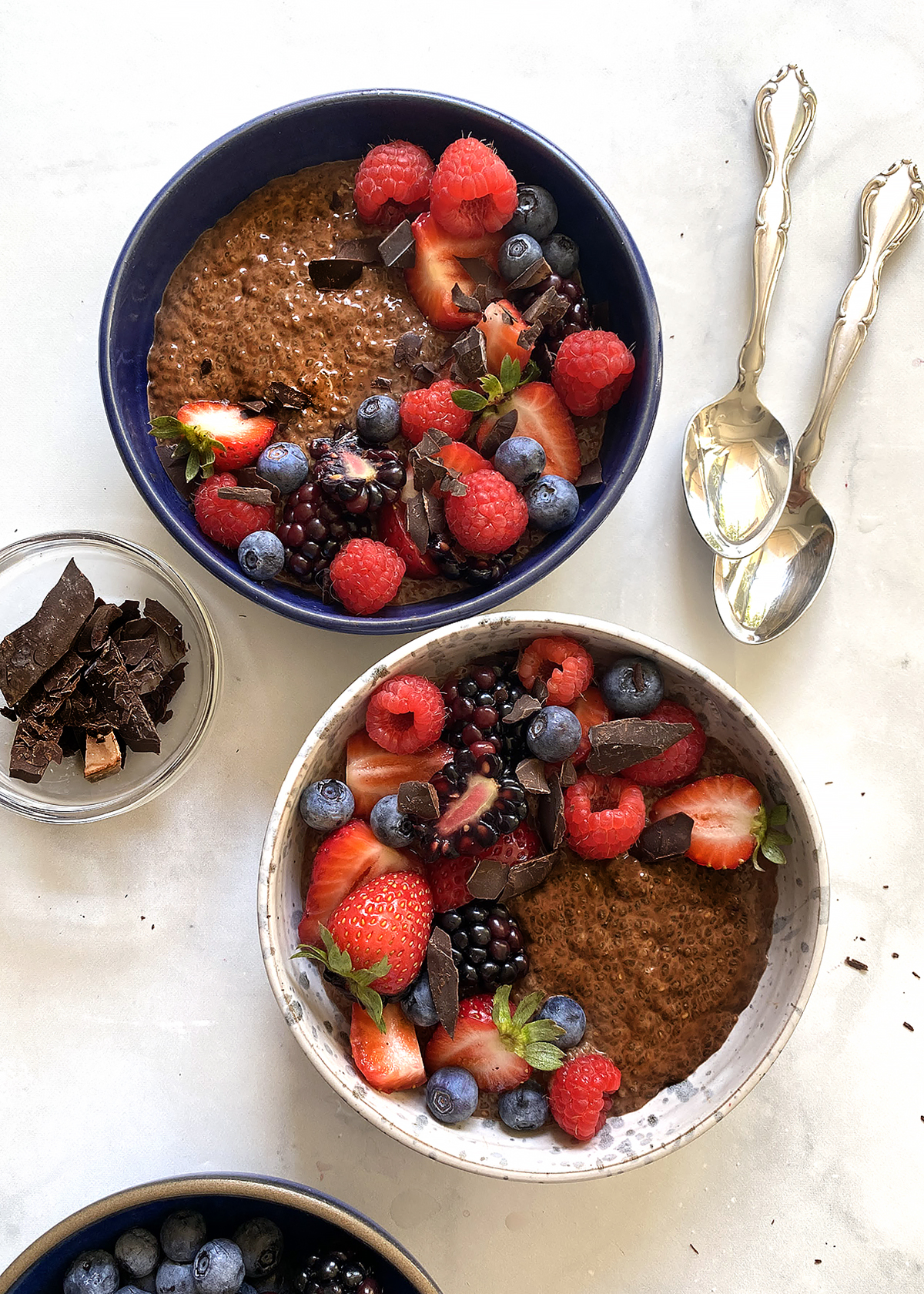 chocolate chia seed pudding topped with berries and chocolate in bowls