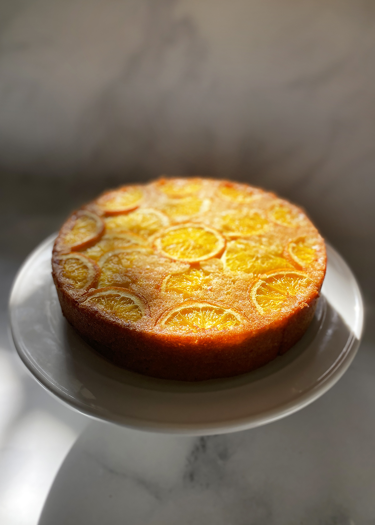 orange olive oil cake on white cake stand