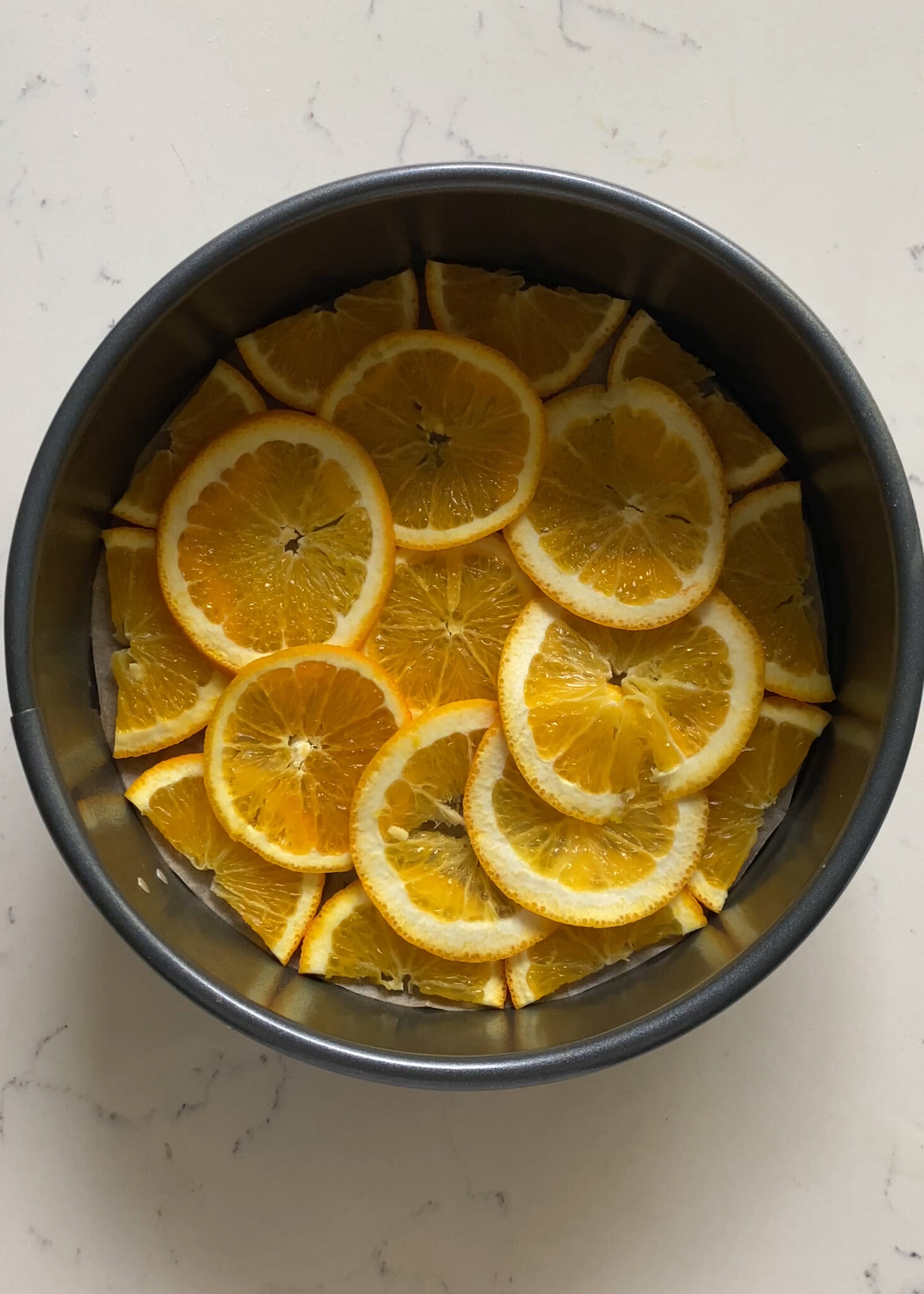 orange slices lining bottom of round cake pan for Orange Olive Oil Cake