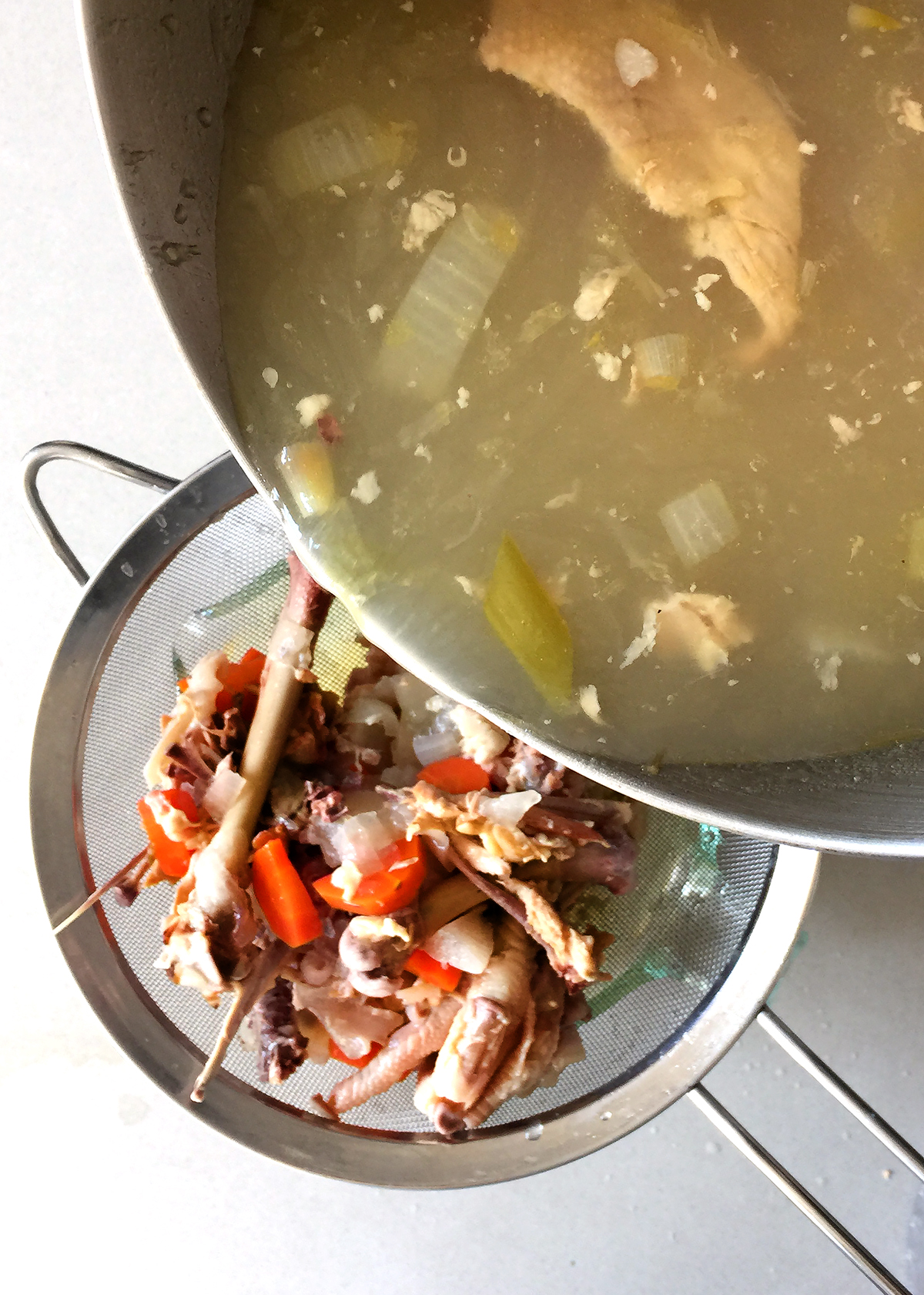 straining bone broth through sieve