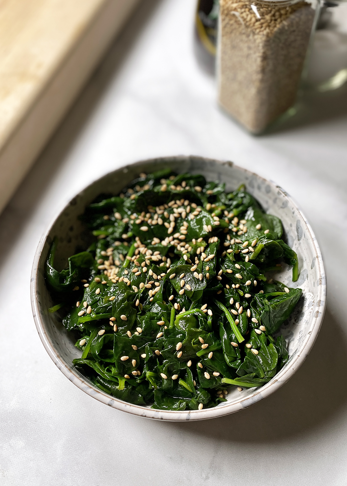 korean spinach shigeumchi namul sprinkled with sesame seeds in shite bowl