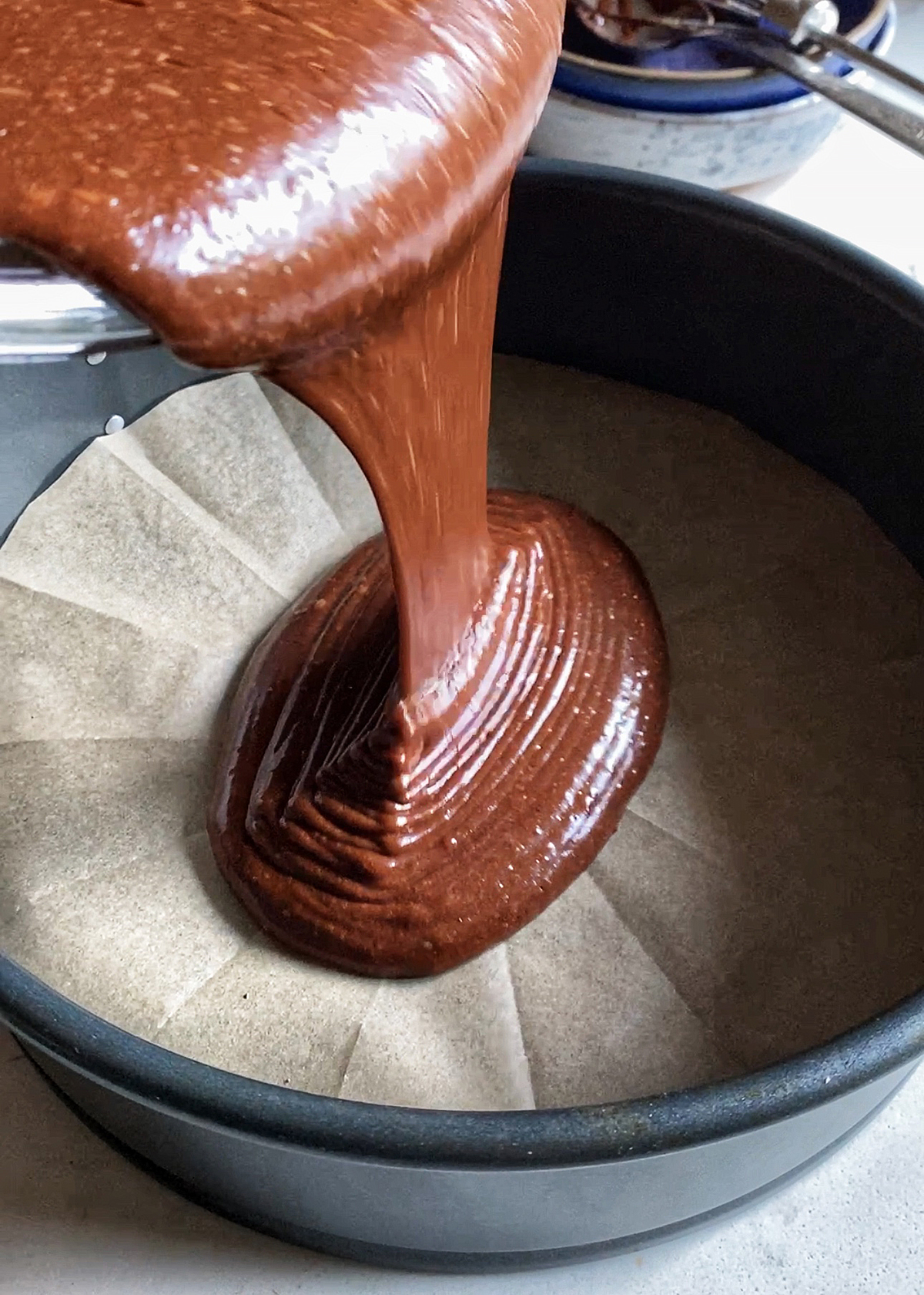 chocolate cake batter pouring into round cake pan