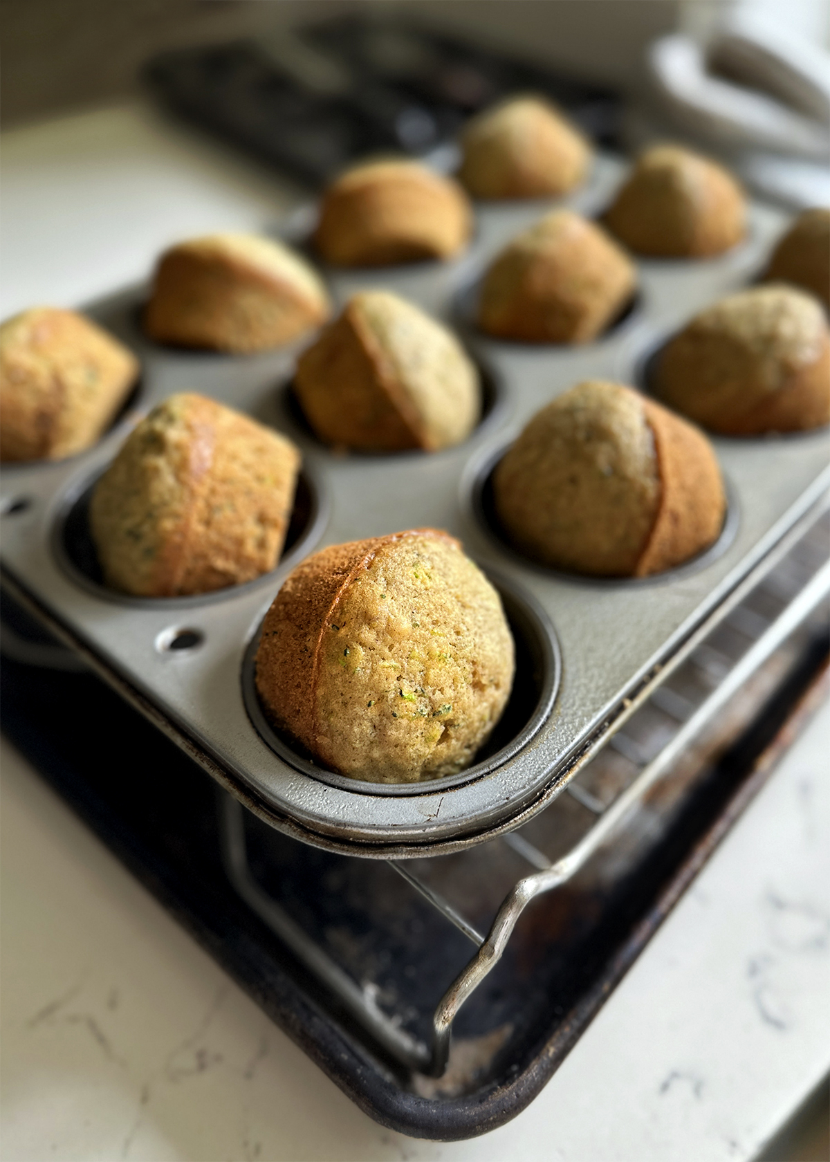 baked zucchini muffins in pan, cooling