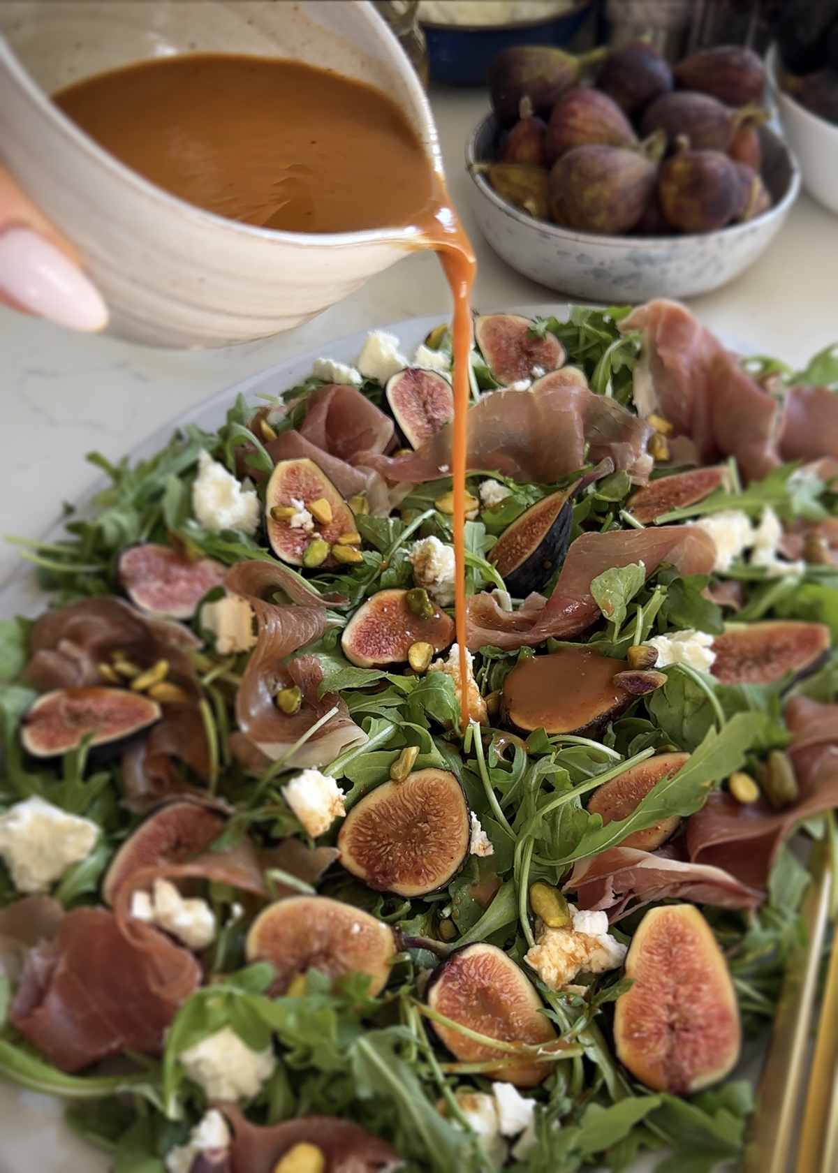 hot honey balsamic vinaigrette pouring over fig salad