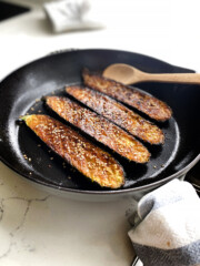 oven roasted zucchini with glaze and sesame seeds in cast iron skillet