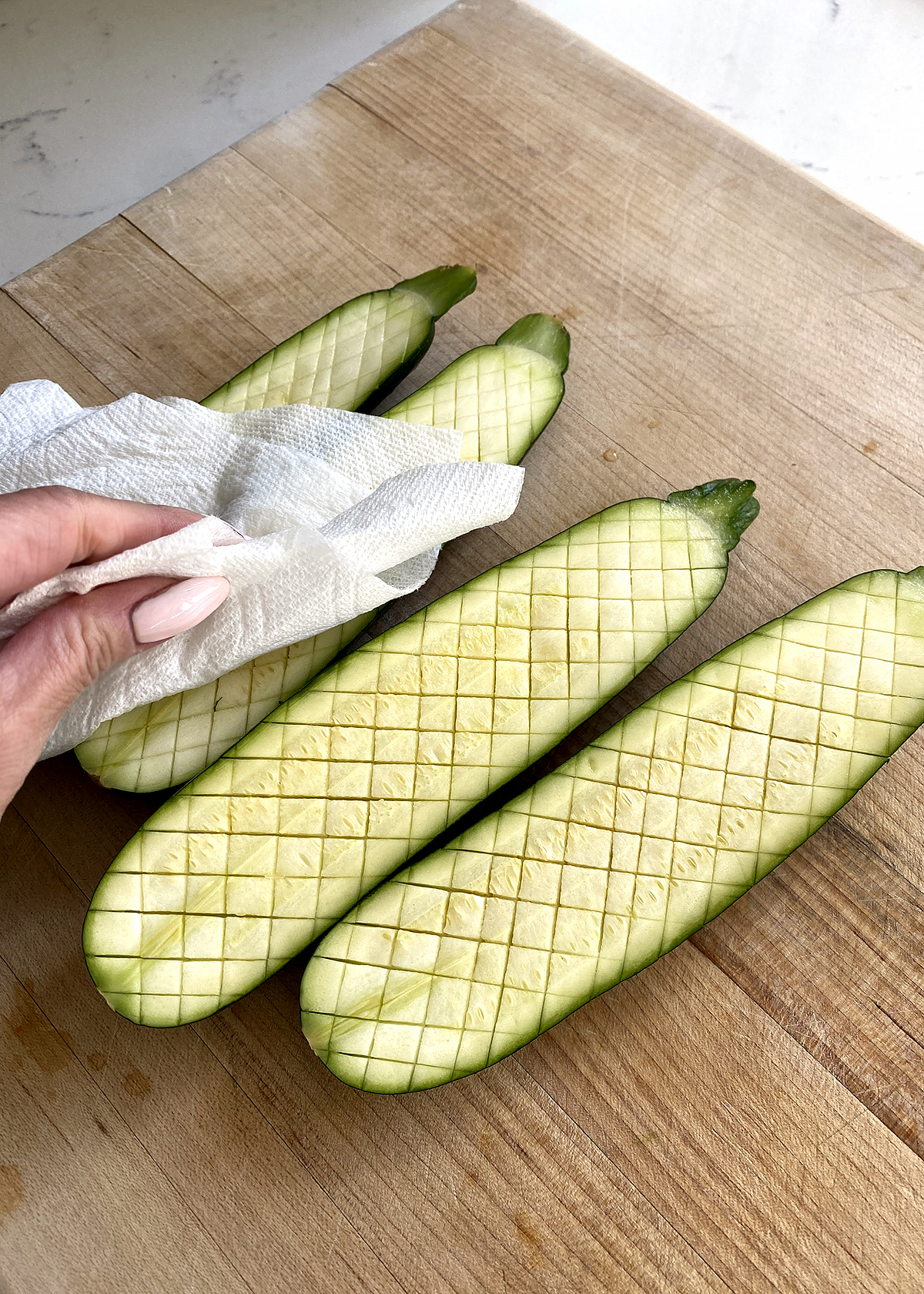 oven roasted zucchini sliced lengthwise, and cut with small cross-hatches thomas keller style, on cutting board, blotted with paper towel