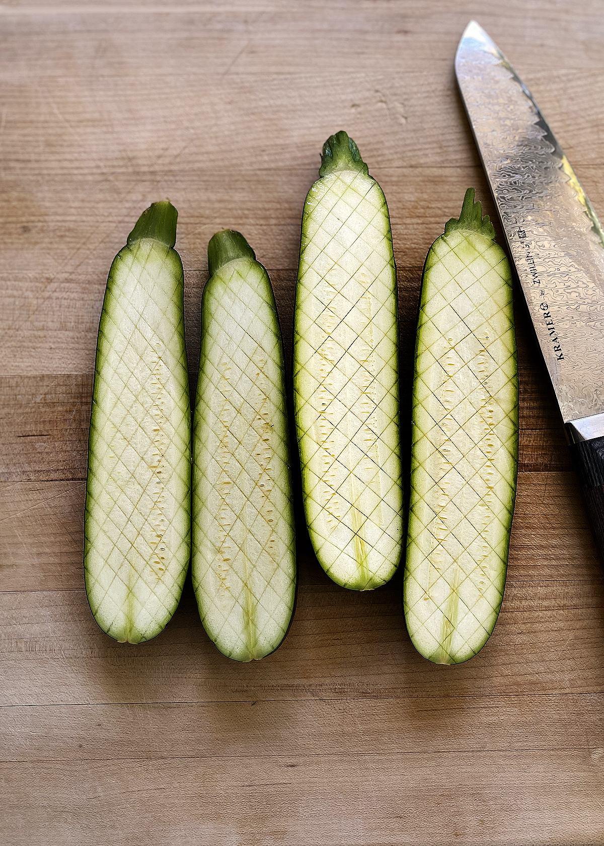 oven roasted zucchini sliced lengthwise, and cut with small cross-hatches thomas keller style, on wooden cutting board
