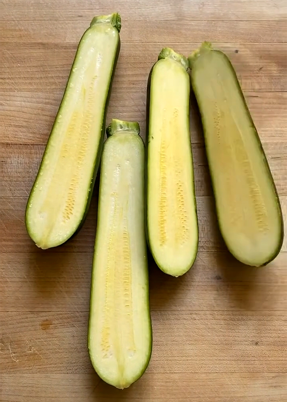 zucchini, sliced lengthwise on wooden cutting board