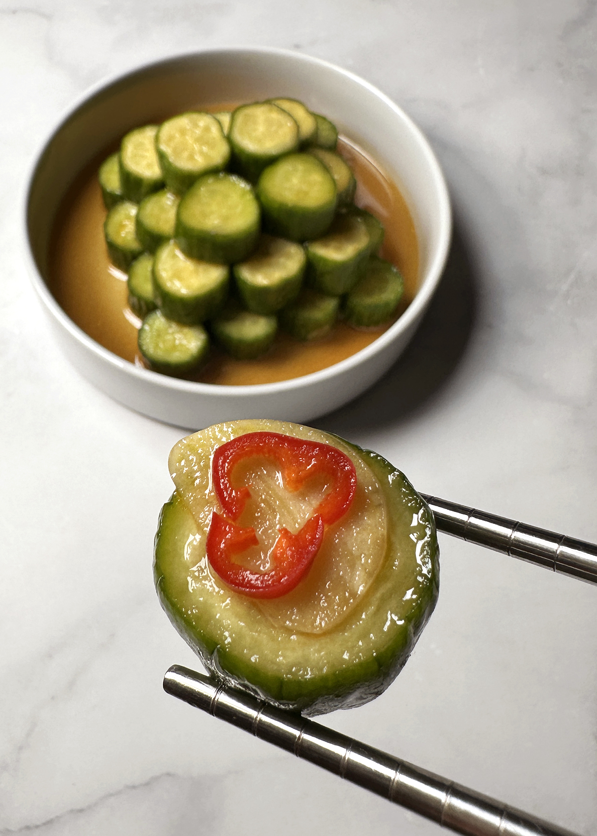chopstick holding spicy cucumber slice