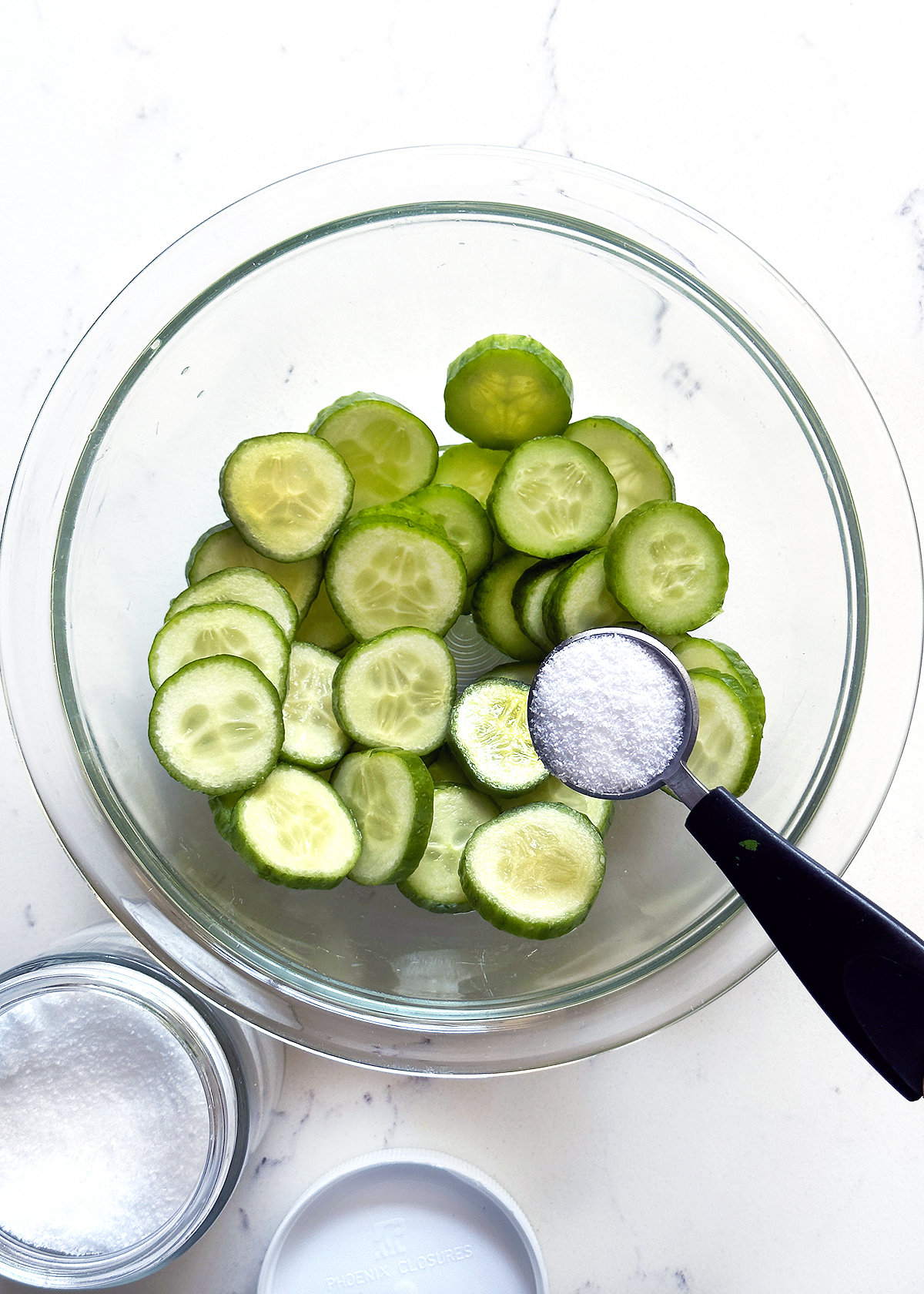 sliced cucumbers salted in glass bowl