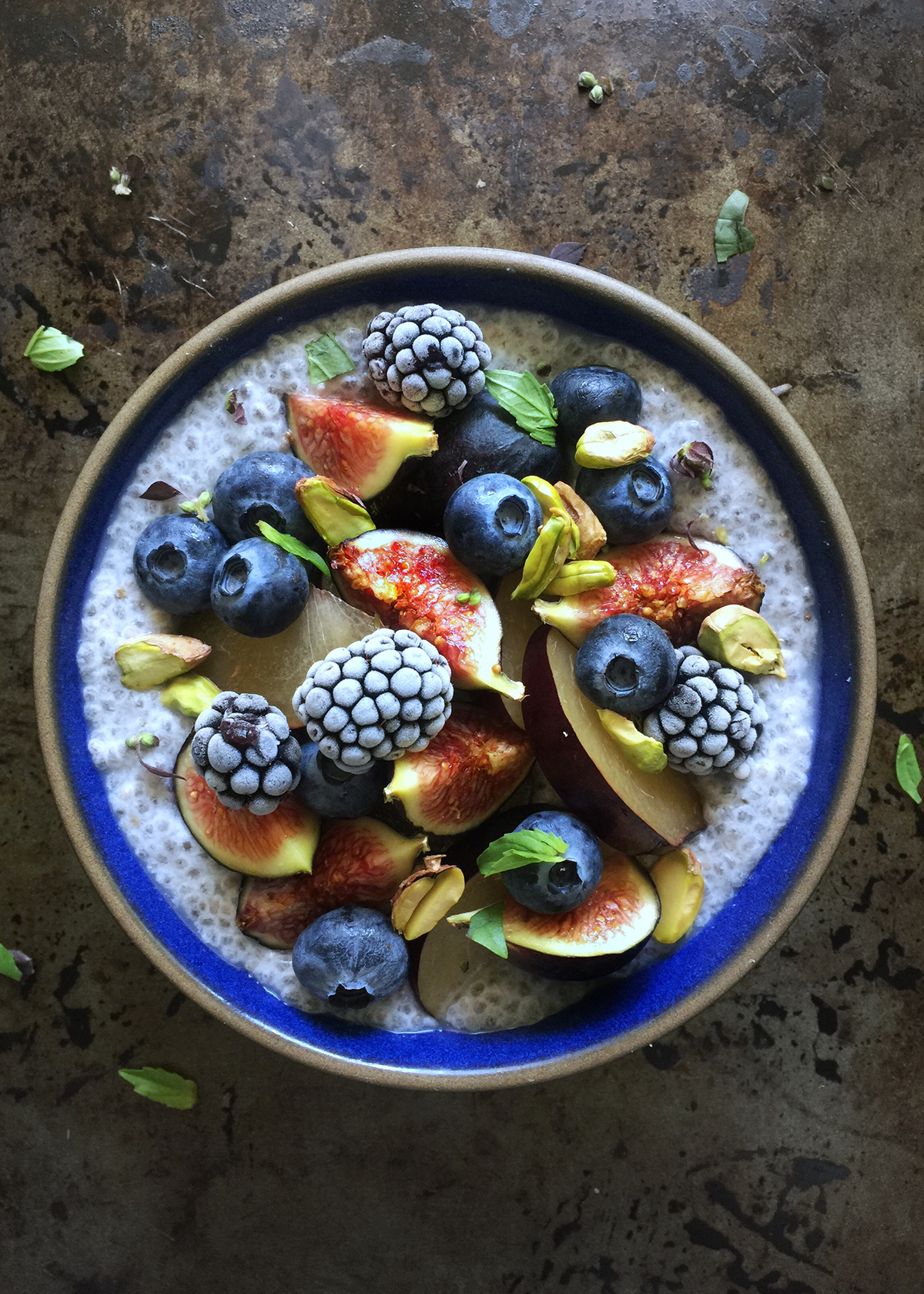 fresh figs and berries on chia seed pudding in blue bowl