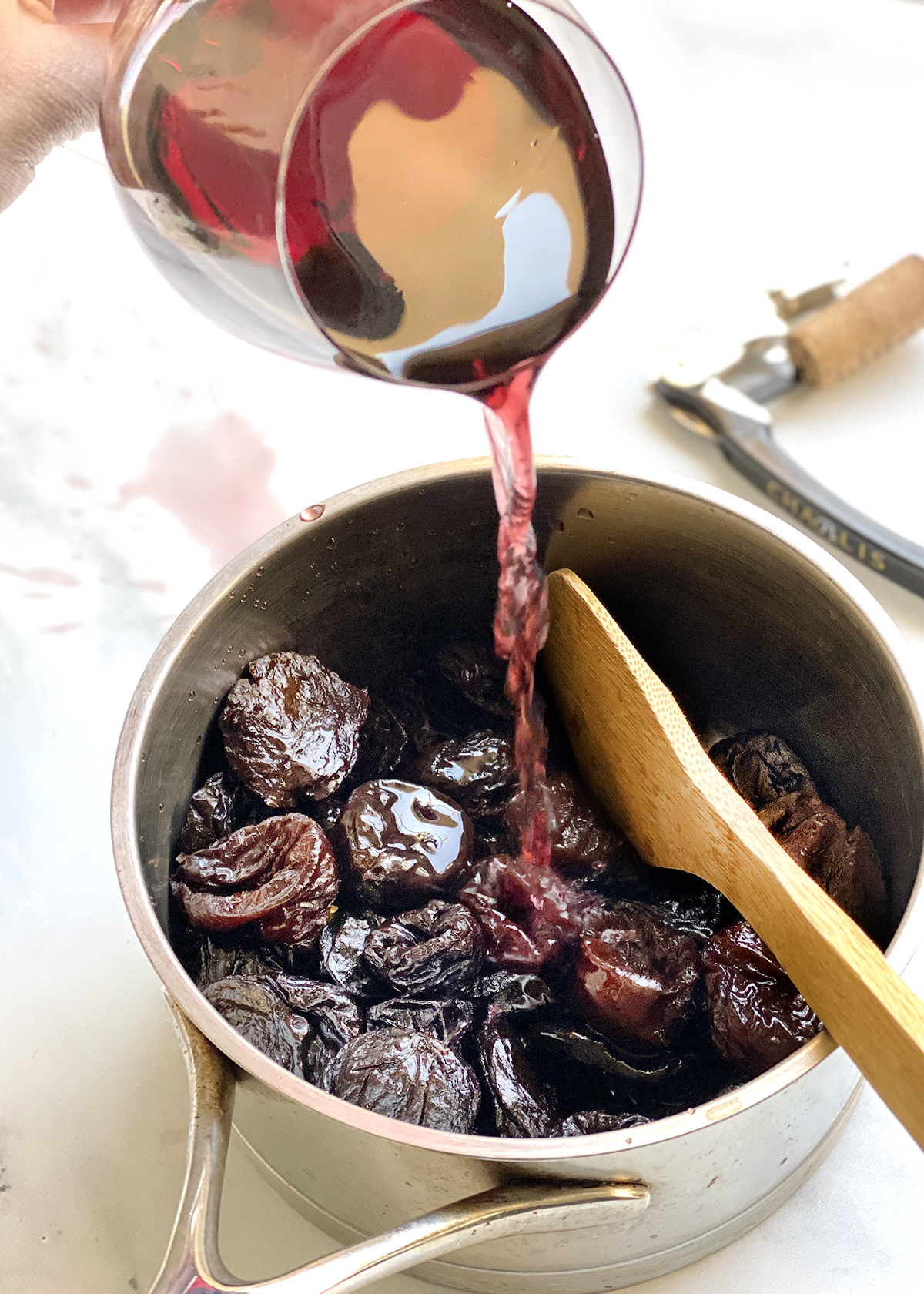 pouring pinot noir wine into pot with prunes