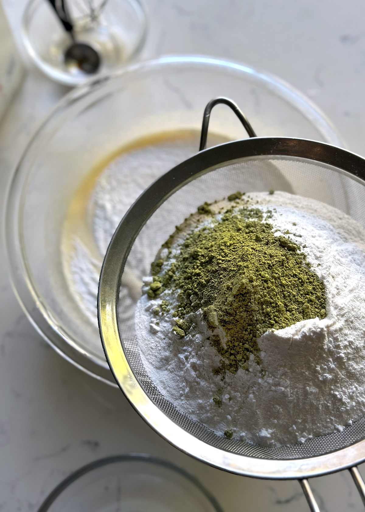 sifting mochiko flour and matcha into liquid ingredients in bowl