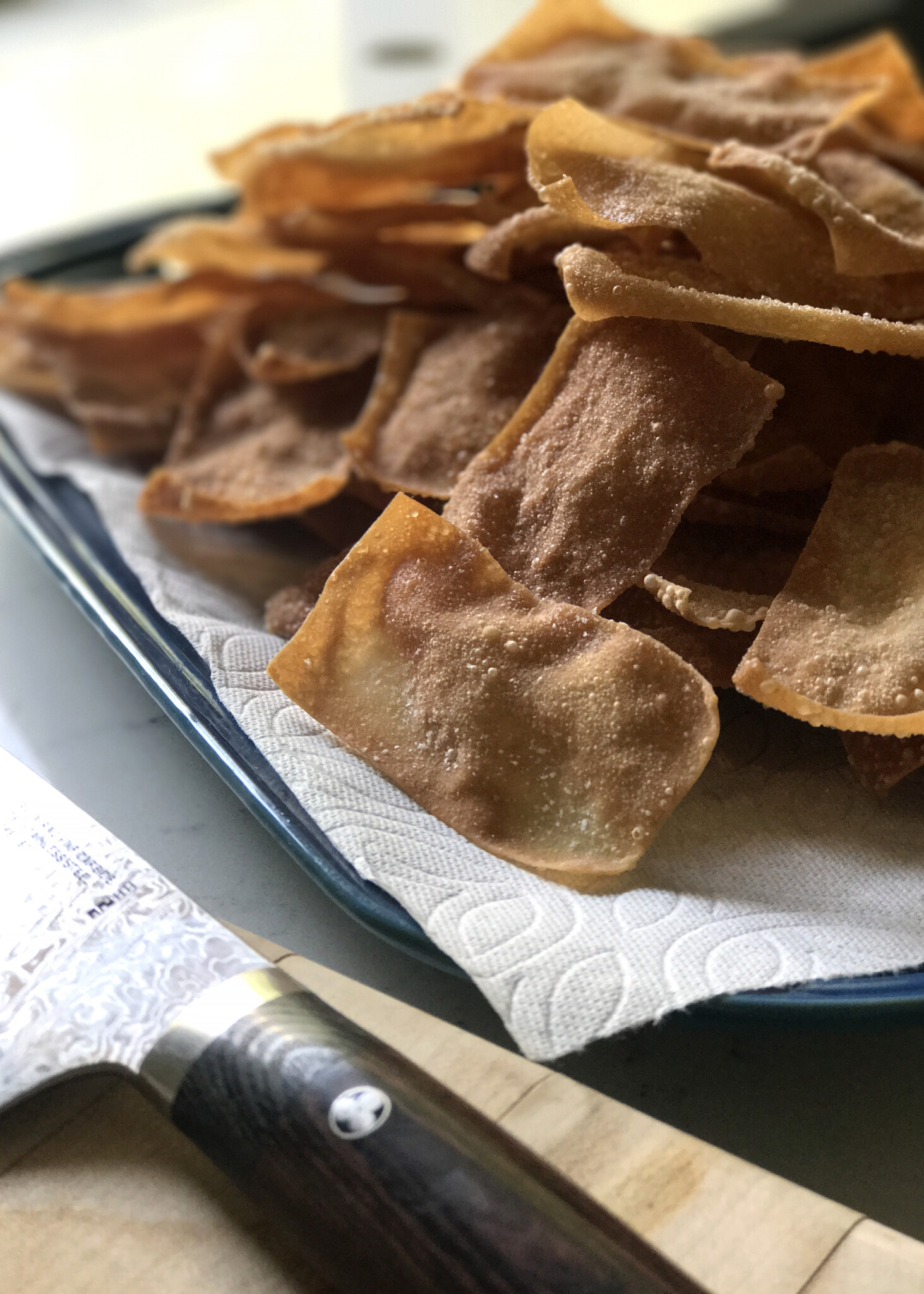 fried wonton wrapper draining on paper towel for chips