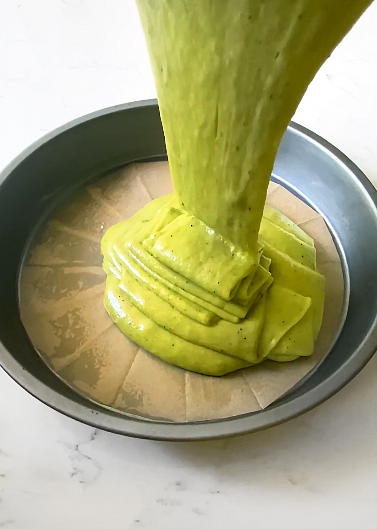 matcha olive oil cake batter pouring into cake pan