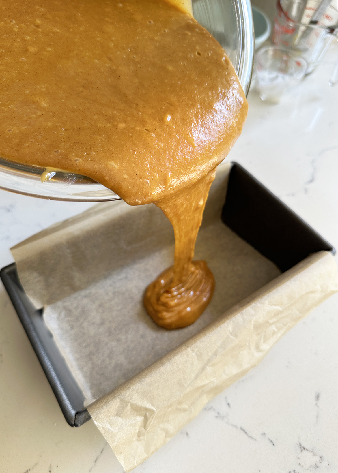 pumpkin bread batter pouring into loaf pan