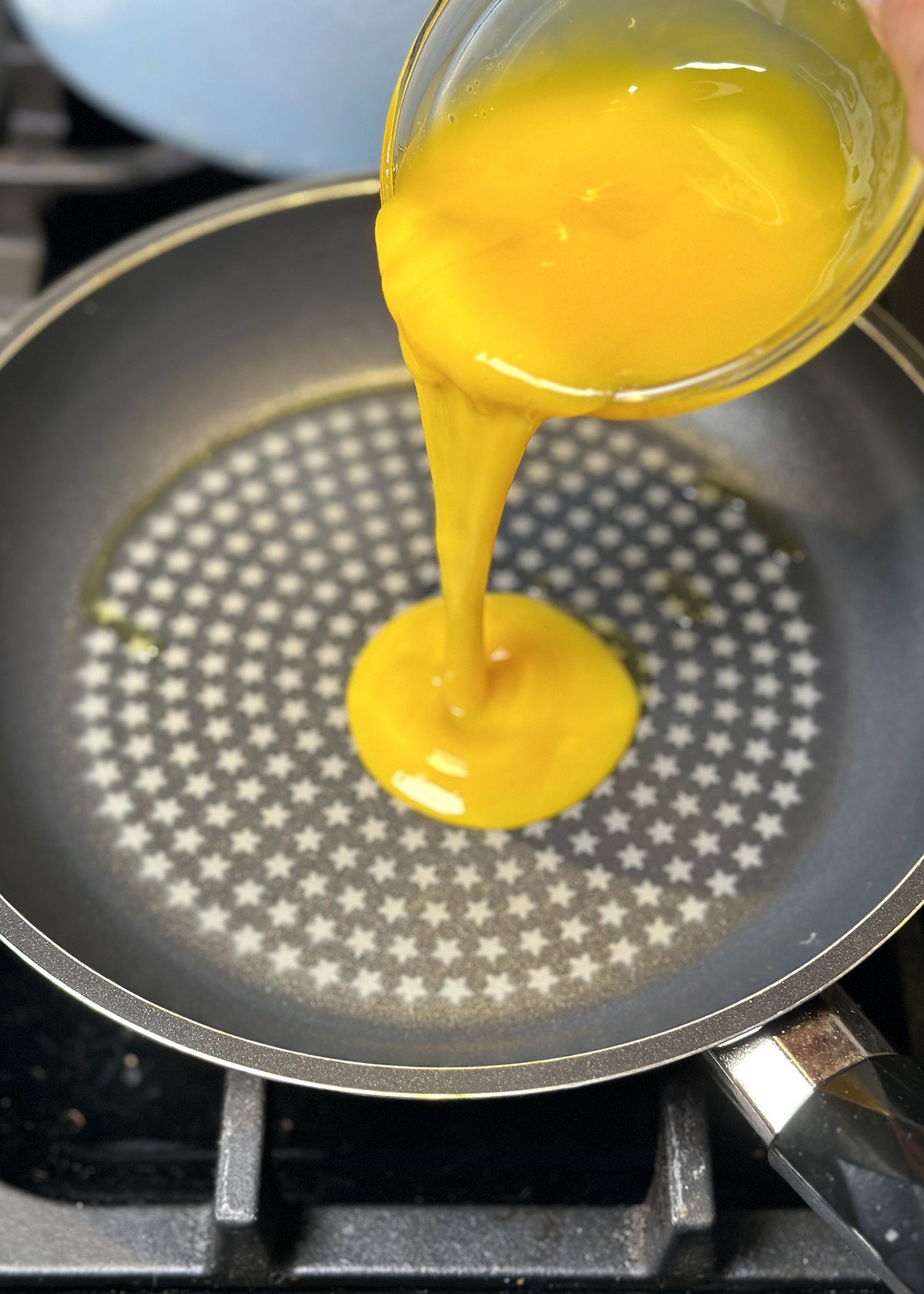 pouring beaten egg yolks into non-stick pan