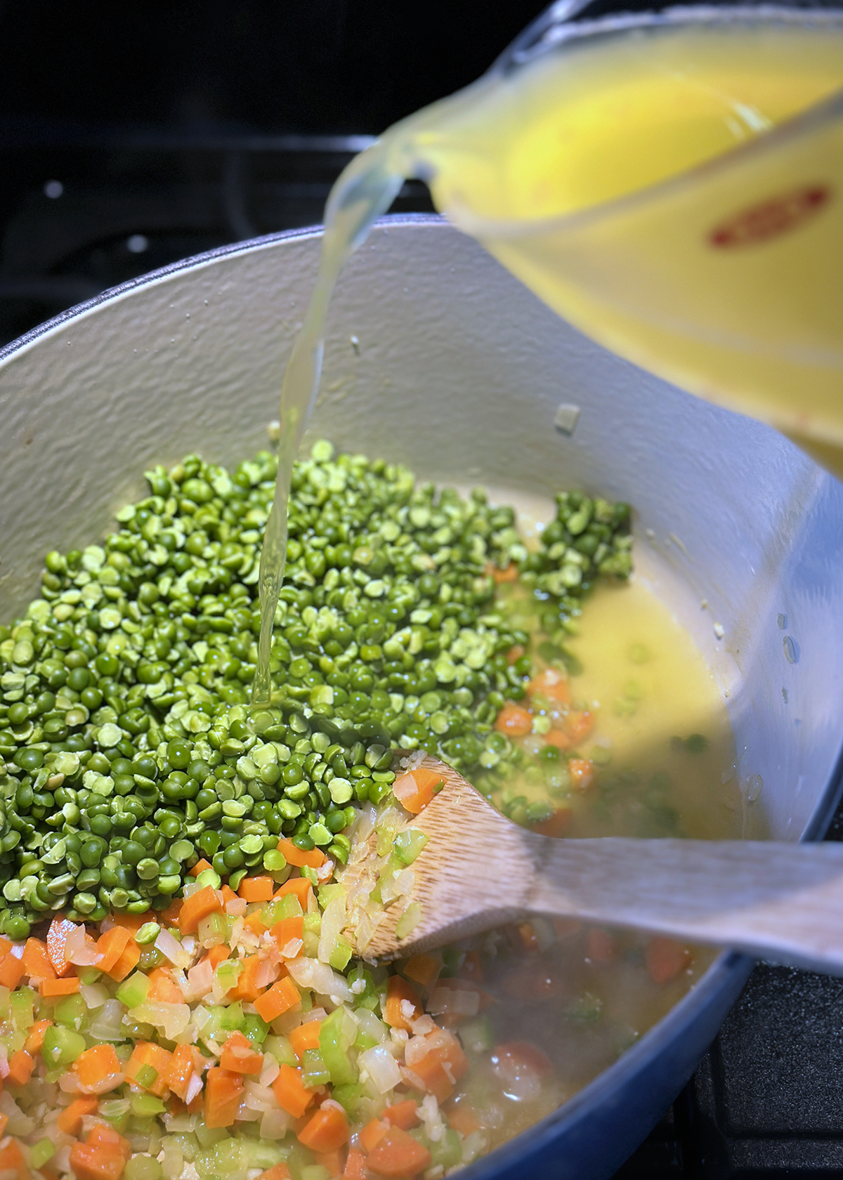 dried split peas in pot with broth pouring in