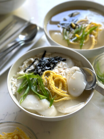 tteokguk, garnished in white bowl for servings