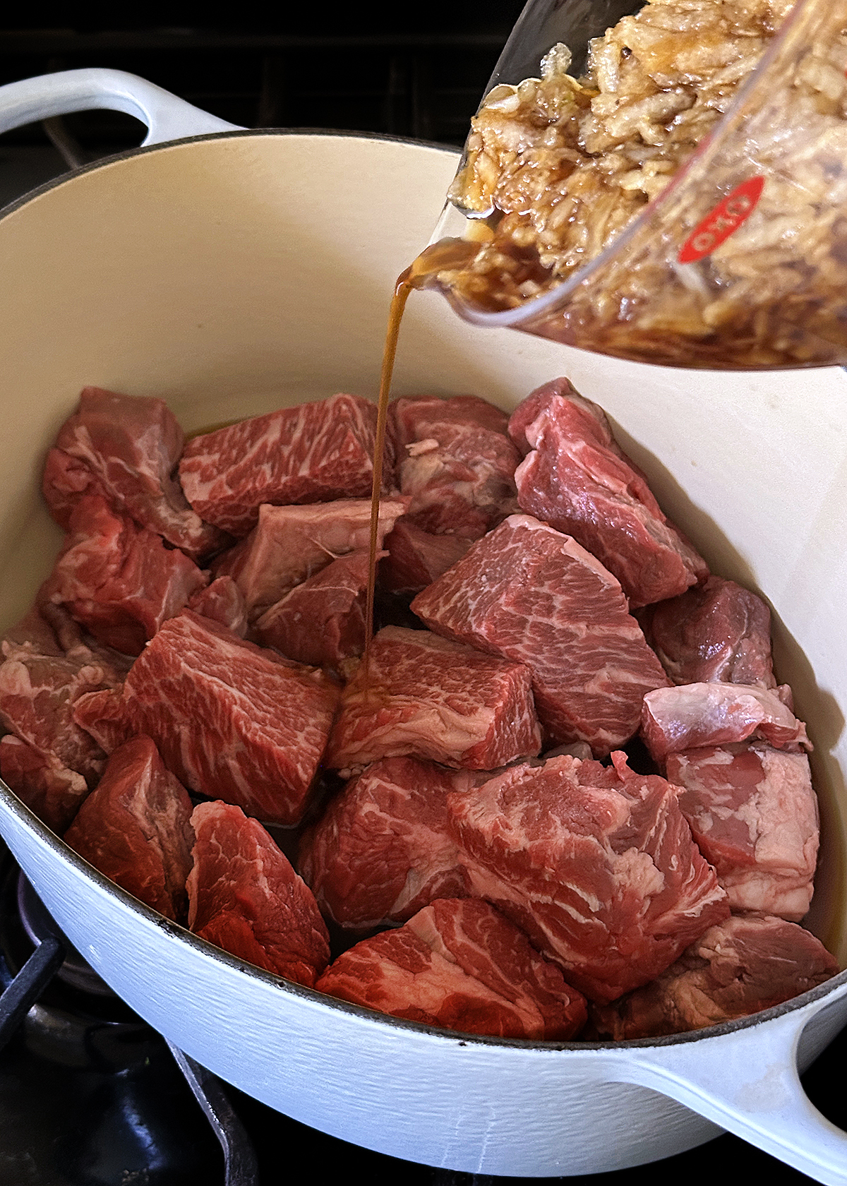 beef stew meat and braising liquid in dutch oven
