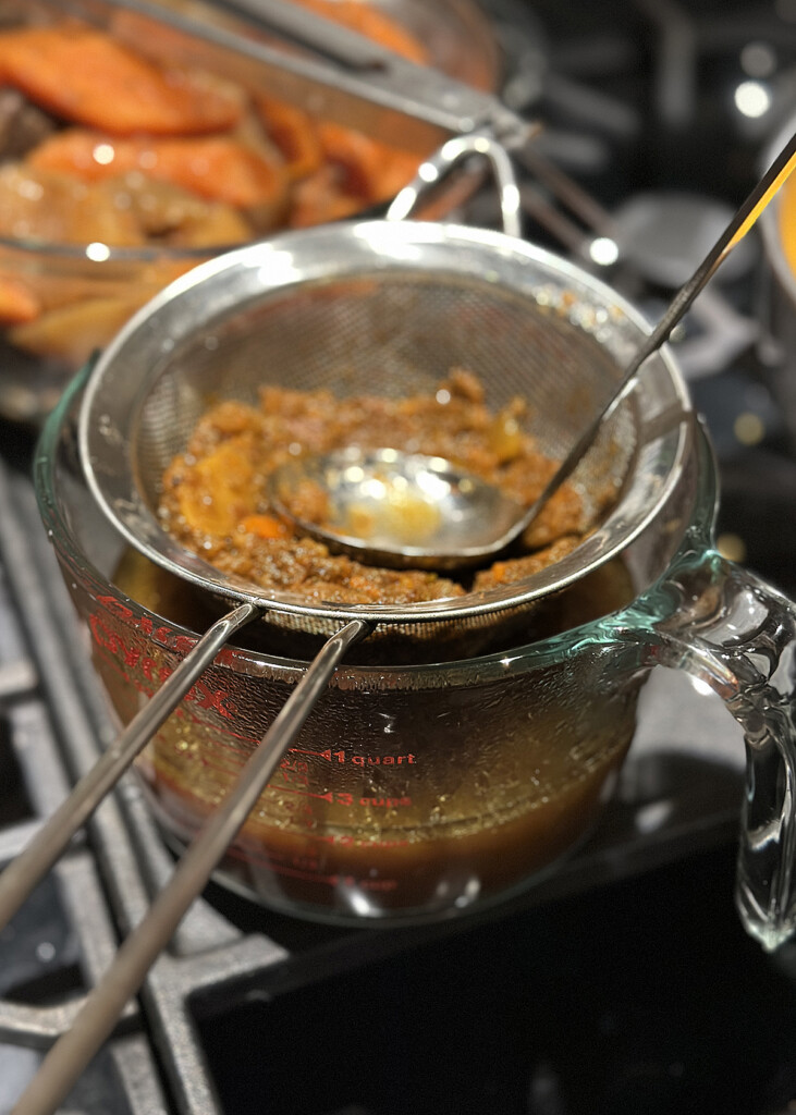 straining galbi jjim korean beef stew through sieve