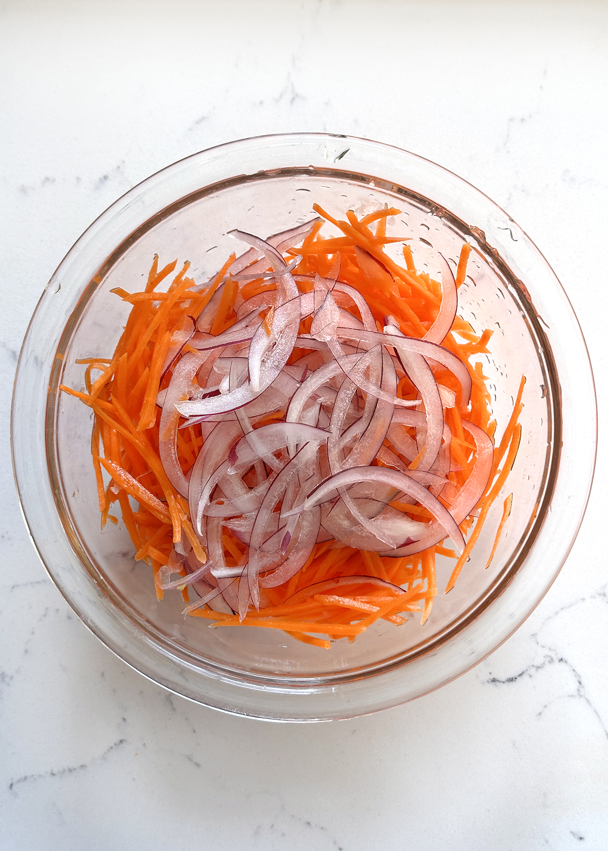 carrots and onions in glass mixing bowl