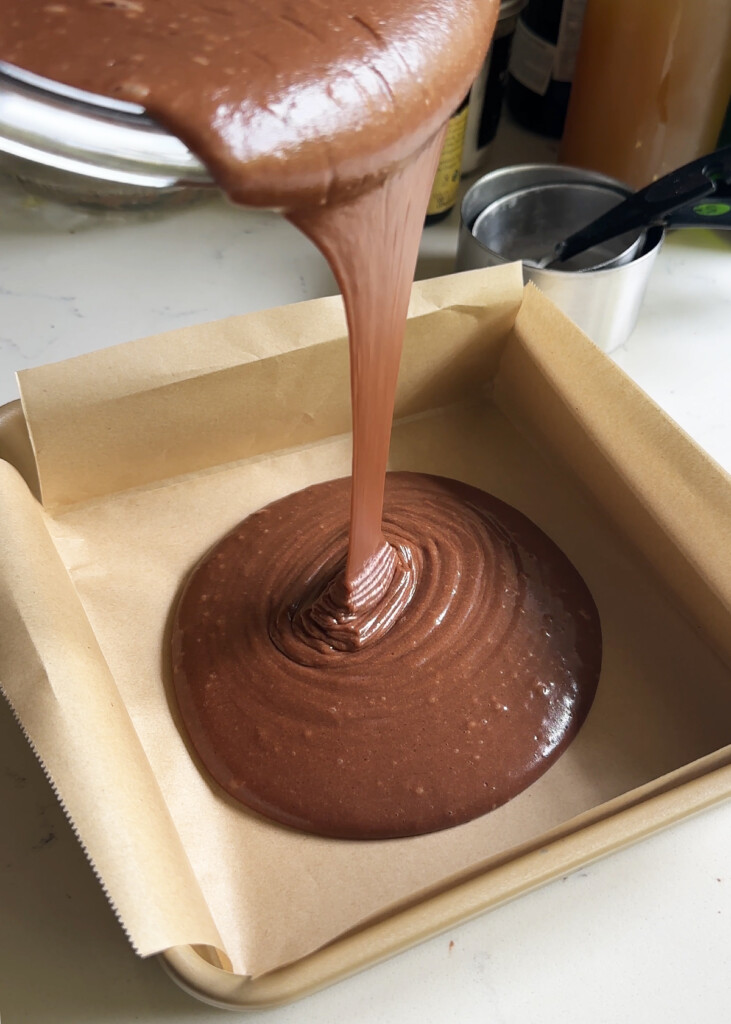 eggless chocolate cake batter pouring into pan