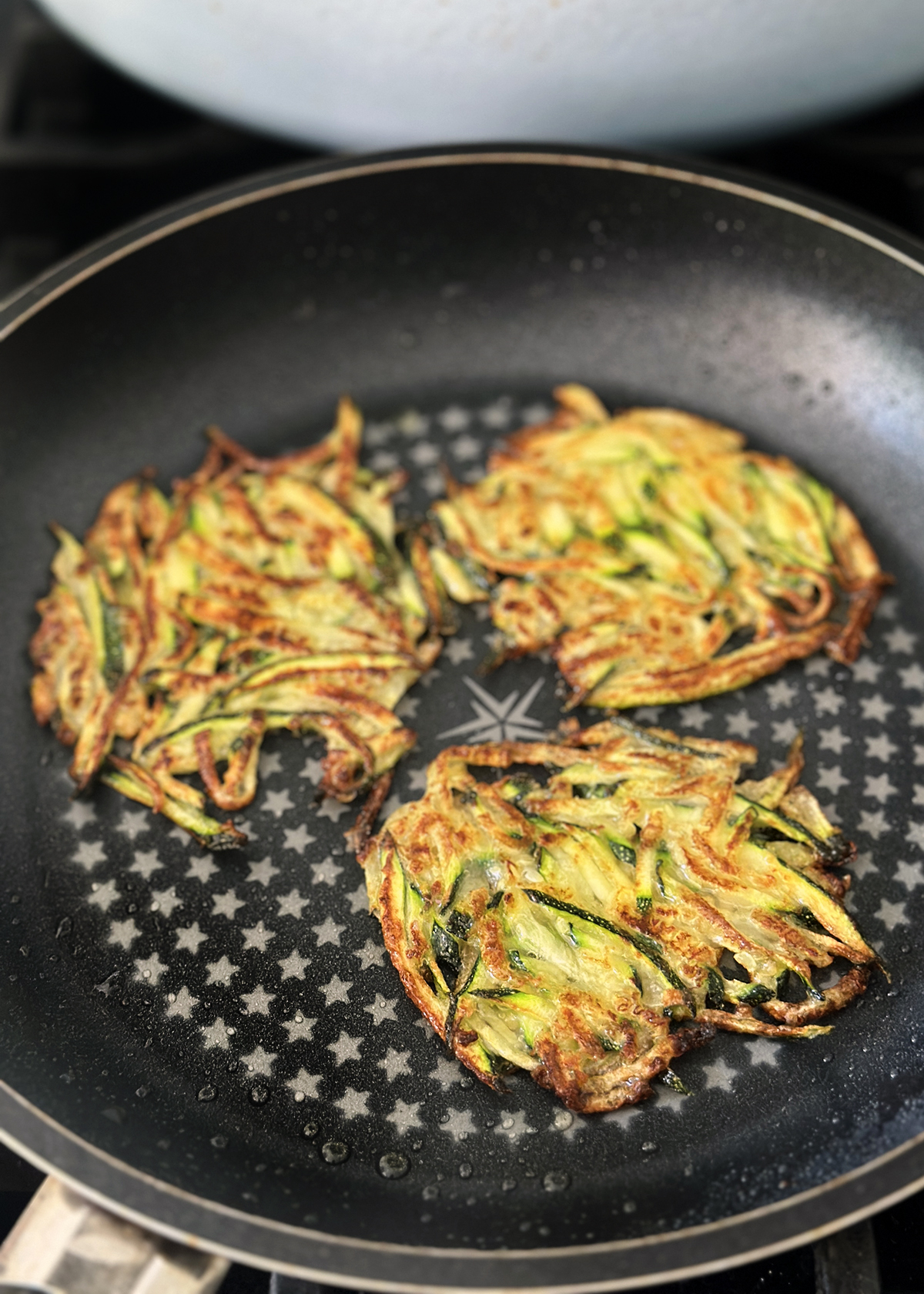 korean zucchini pancakes in pan, flipped over