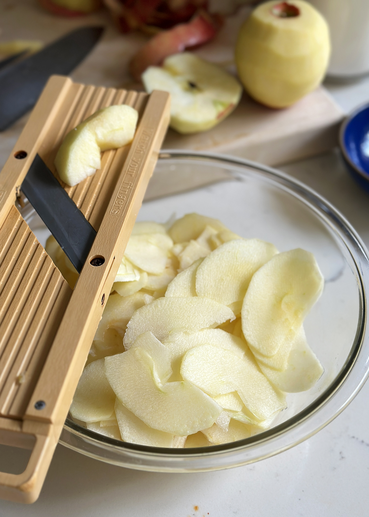sliced apples in bowl with mandoline