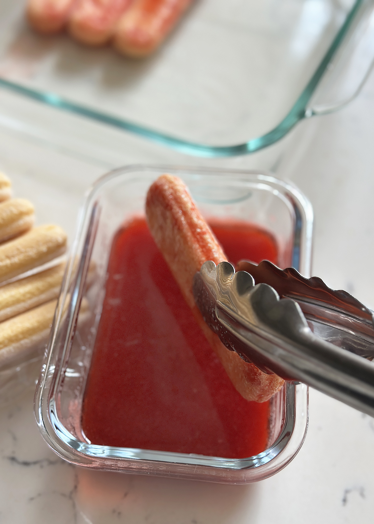 dipping ladyfingers in strawberry syrup