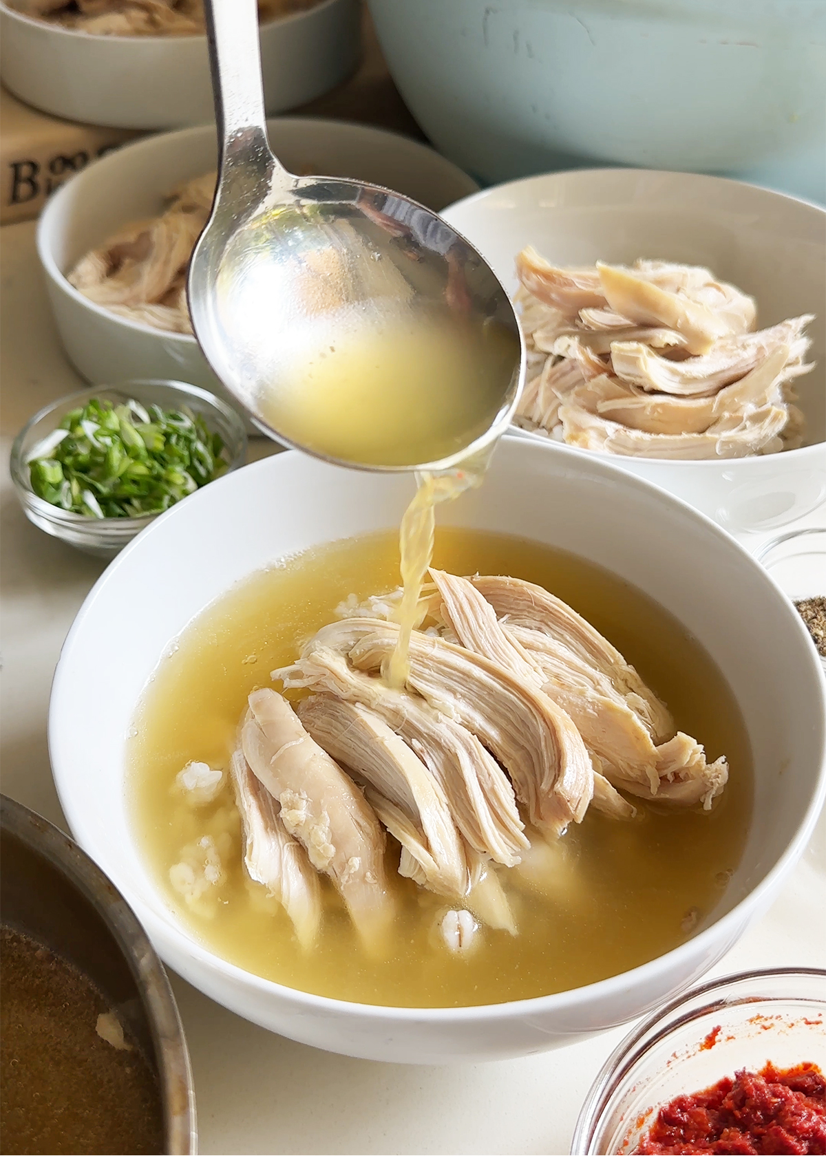 chicken bone broth laadling into soup bowl