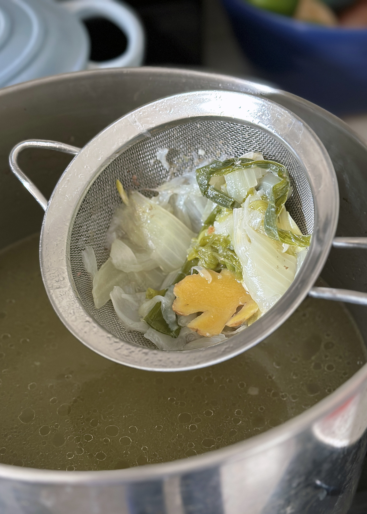 straining aromatics from chicken bone broth